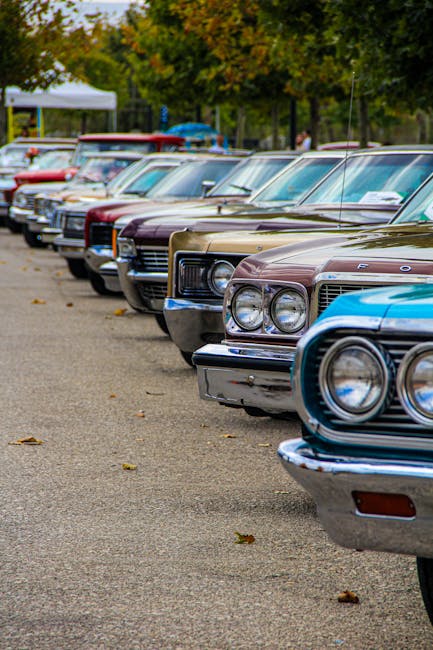 Line of colorful vintage cars parked outdoors, showcasing classic automotive design.