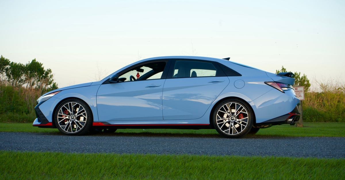 Side view of a blue Hyundai Elantra N parked on a road with grassy surroundings in Kissimmee, FL.
