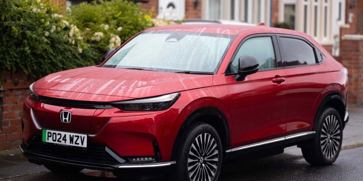 A vibrant red Honda SUV parked on a rainy suburban street, showcasing modern design.