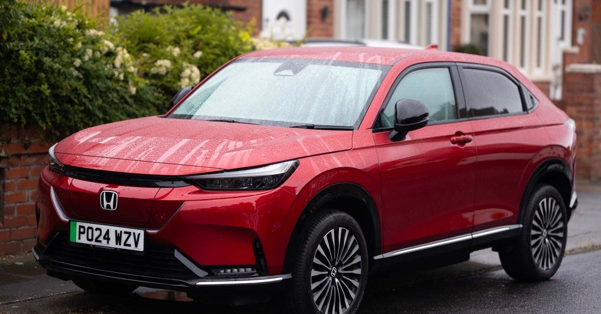 A vibrant red Honda SUV parked on a rainy suburban street, showcasing modern design.