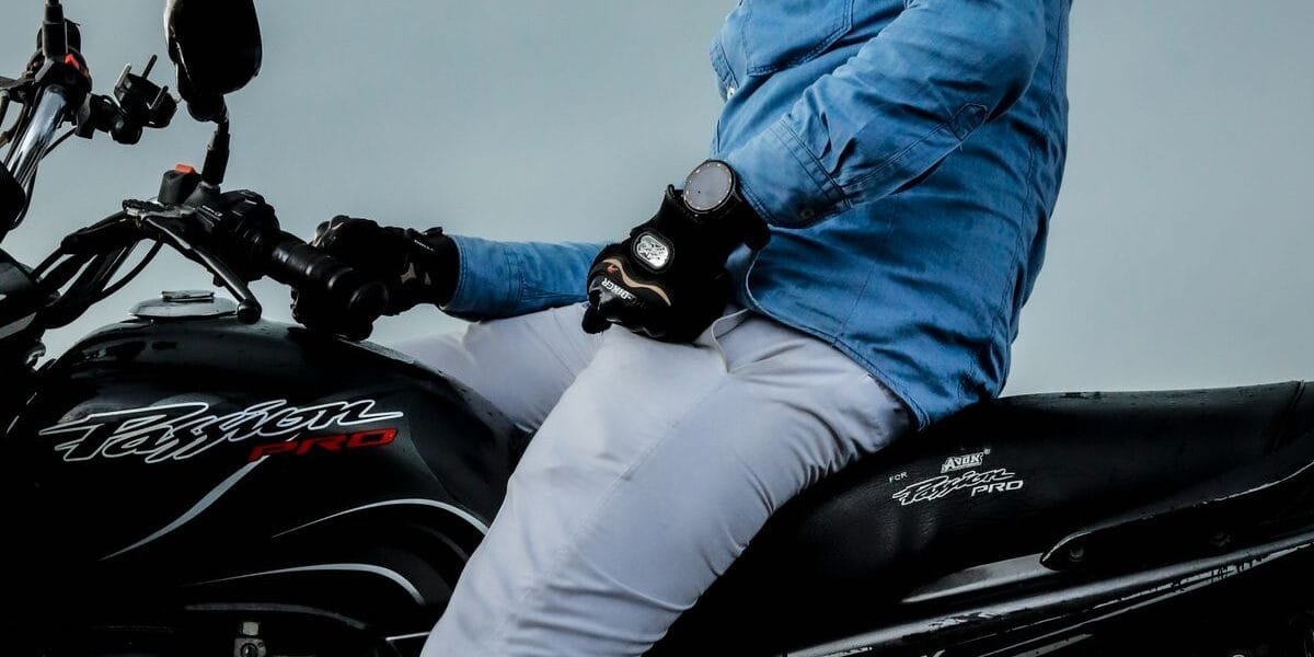 Low-angle shot of a motorcyclist wearing a blue jacket and helmet, riding outdoors.