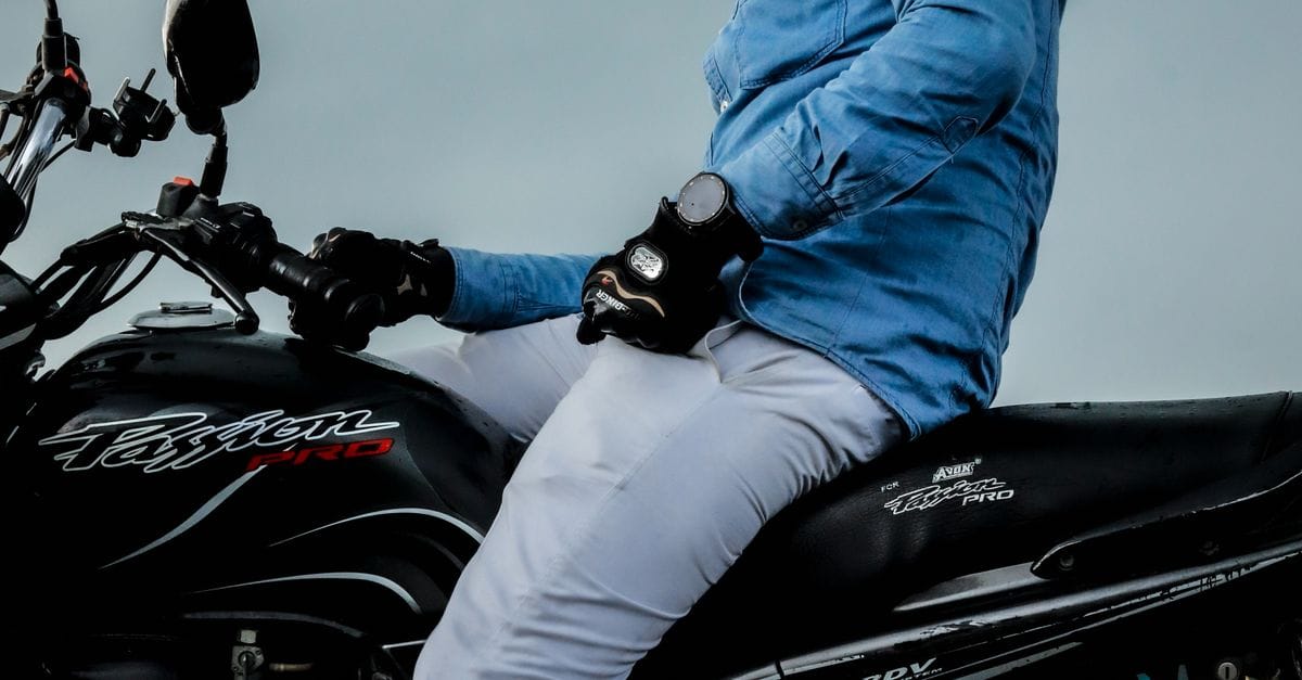 Low-angle shot of a motorcyclist wearing a blue jacket and helmet, riding outdoors.